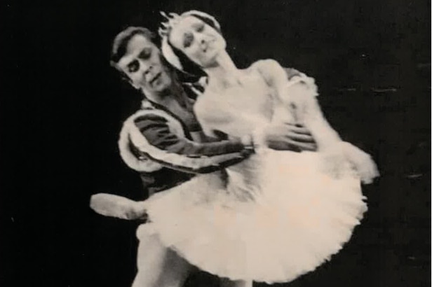 A black and white image of a male and female ballet dancer dancing together on stage.