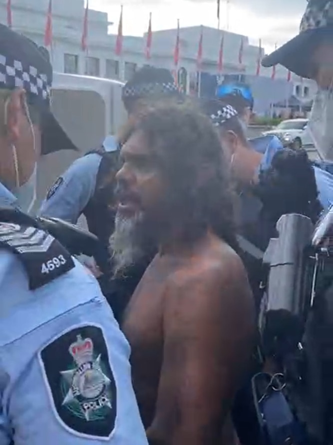 Police surround a shirtless man.