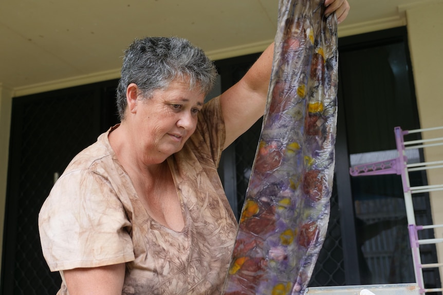 a woman holds up a coloured piece of silk