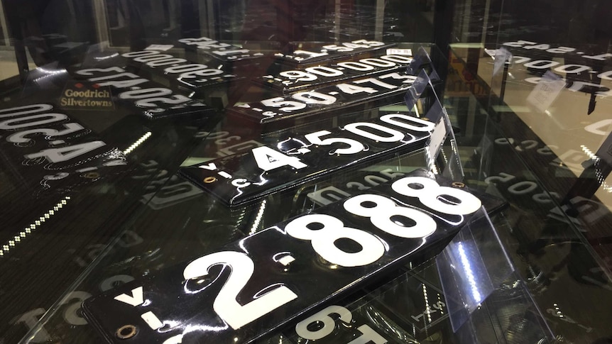A number of registration plates sit in a display cabinet.