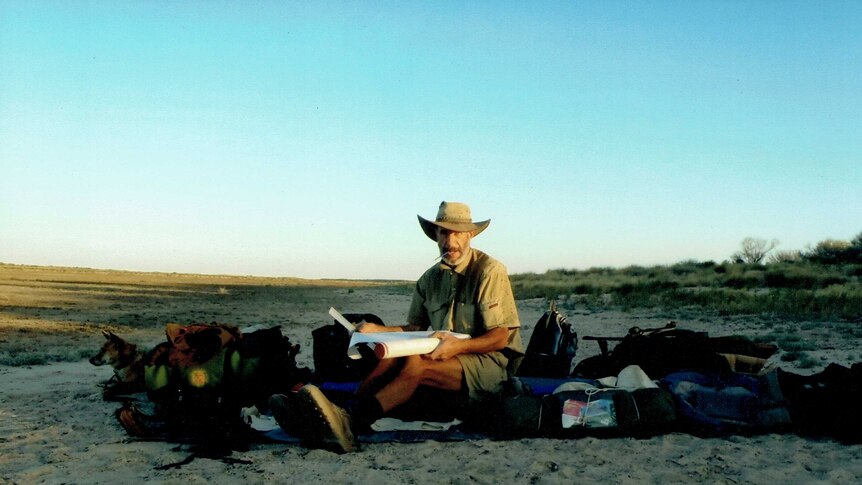 Outback adventurer Owen Davies with his dingo on a sand dune in western Queensland
