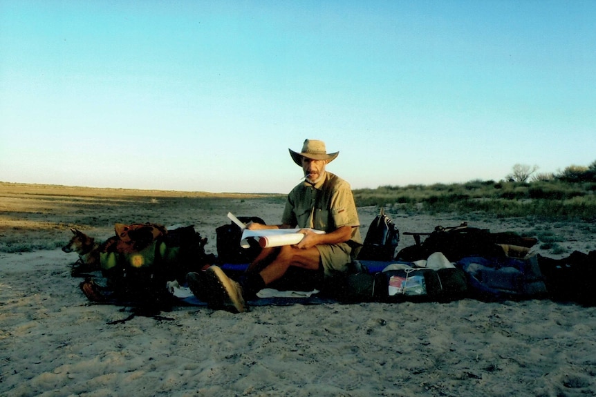 Outback adventurer Owen Davies with his dingo on a sand dune in western Queensland