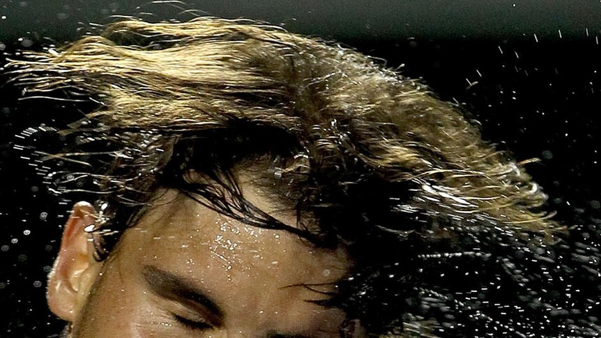 Rafael Nadal flicking sweat off his head.
