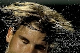 Rafael Nadal flicking sweat off his head.