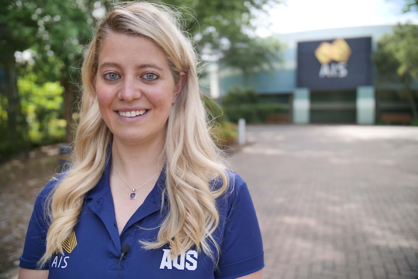 Head shot of a woman standing our the front of an Australian Institute of Sport building in Canberra