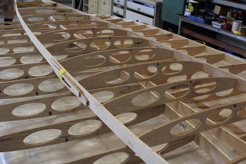 Wooden surfboard frames stacked on a work bench.