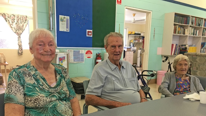 Two elderly women and an elderly man sitting at a table.