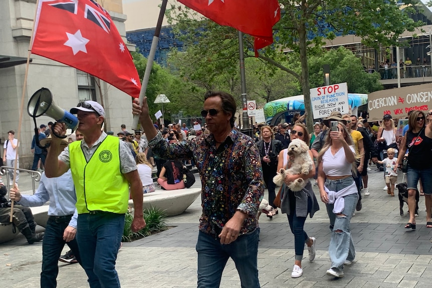 A group of people holding placards marches through the Perth CBD.