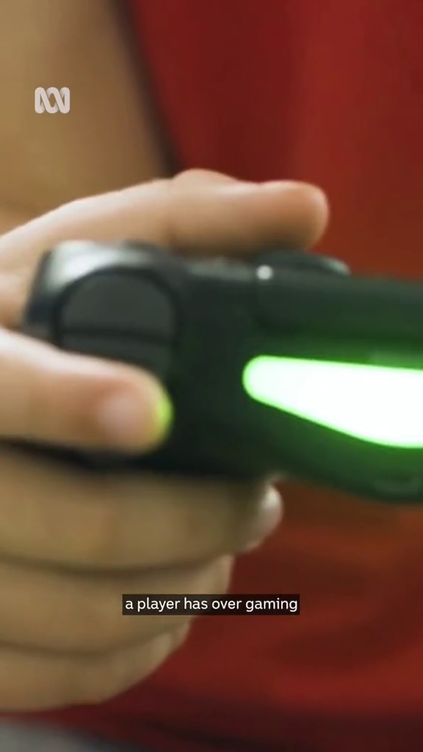 A gaming controller sits in the hand of a young person with a light skin tone