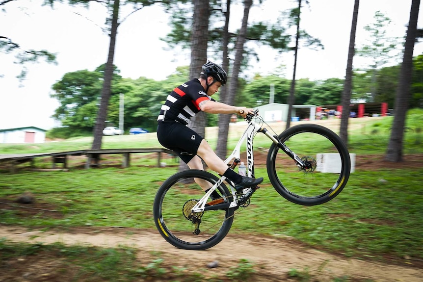 Man rides mountain bike on back wheel