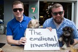 A man holds a sign saying "the emotional investment".