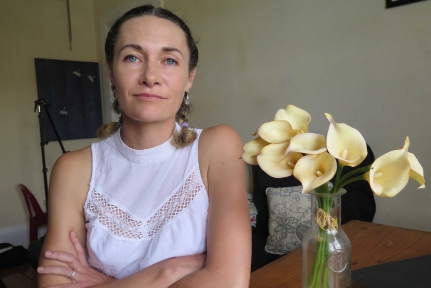 A woman looks at the camera as she poses for a photograph while seated at a table.