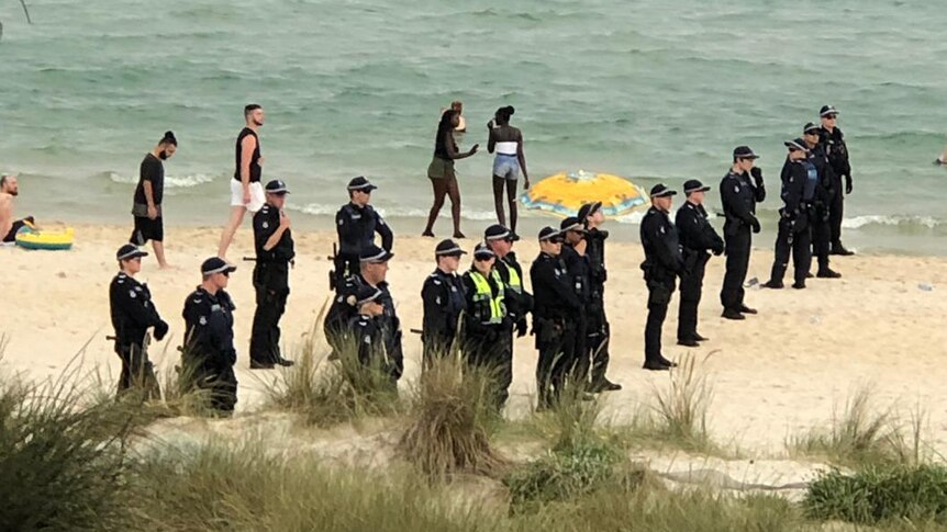 Police officers stand in a line on the sand at Chelsea Beach.