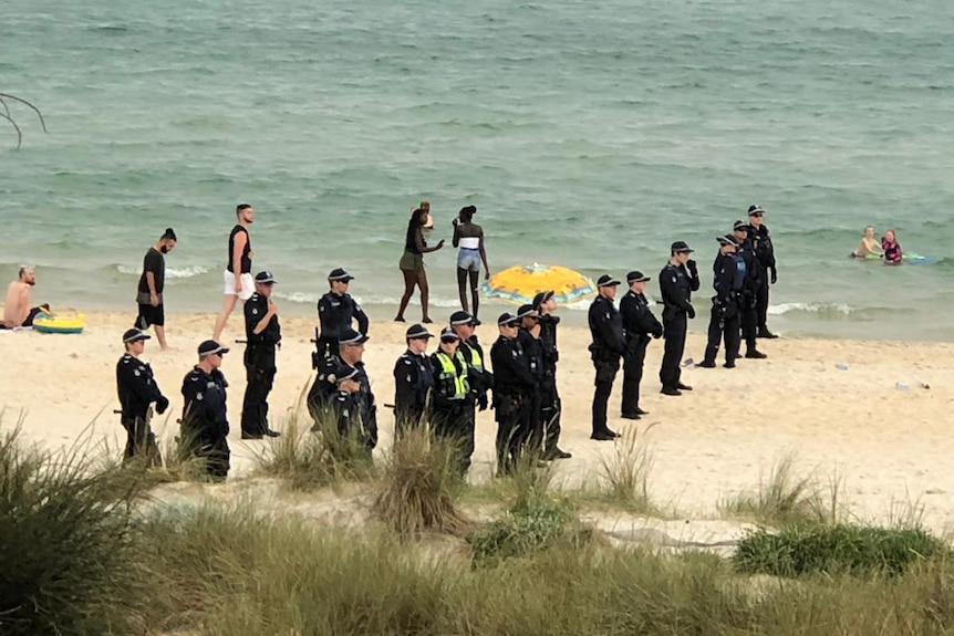Police officers stand in a line on the sand at Chelsea Beach.