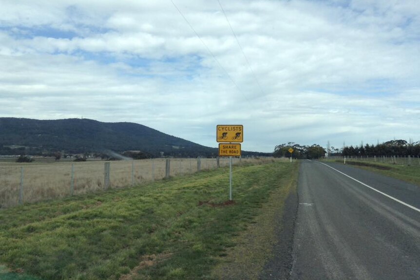 A photo of a cyclist beware sign on the side of a country road 