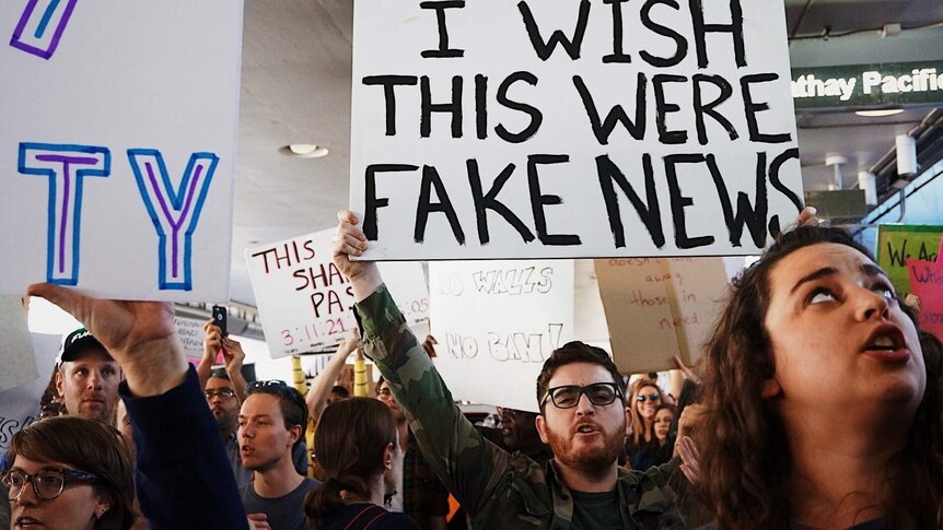 Person holding 'I wish this were fake news' protest sign at a protest in story about our biases and news