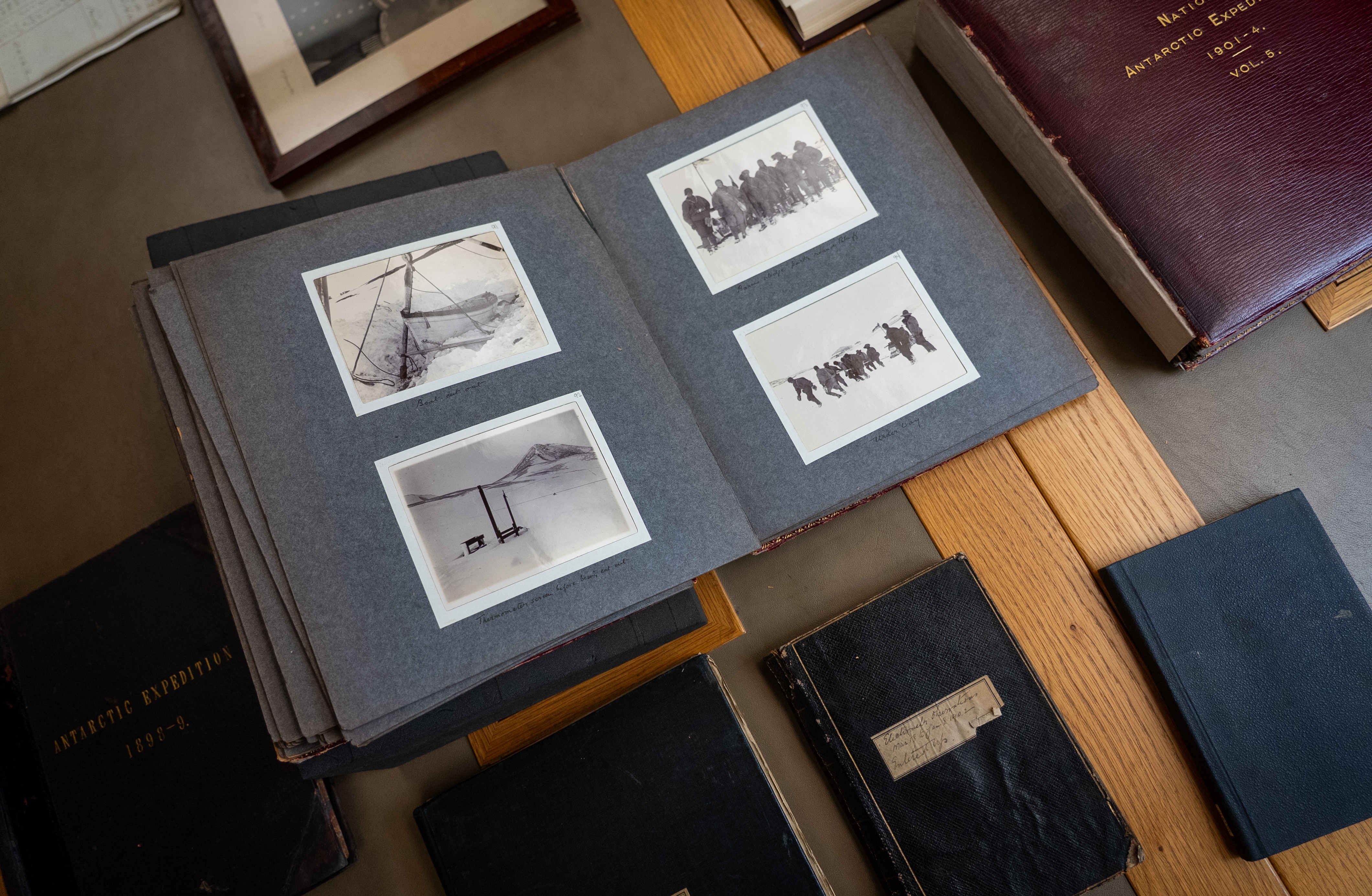 Black and white photos from Shackleton's Antarctic expedition sit in bound books