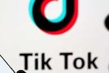 Dark outline of person holding image of phone with Tik Tok on it