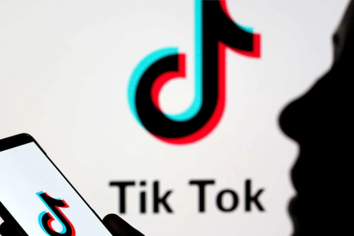 Dark outline of person holding image of phone with Tik Tok on it