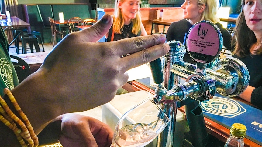 A glass of wine is being poured at a bar using the same type of tap used to pour a beer
