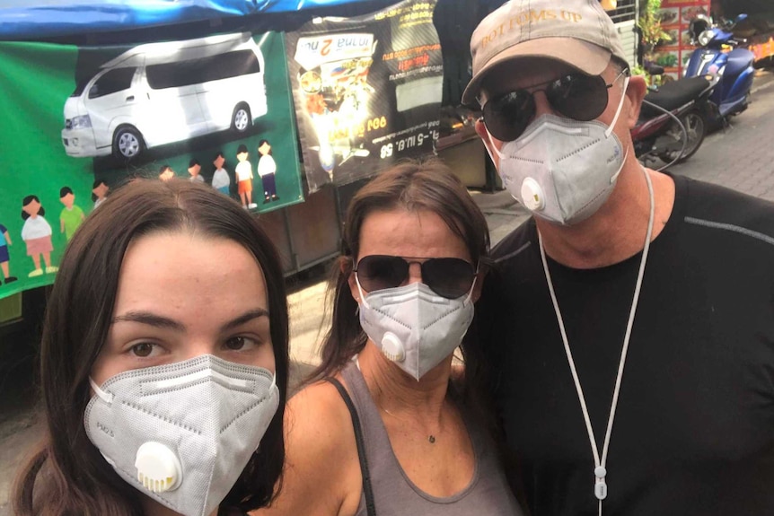Selfie of Evie, Sharon, and Karl Radonich wearing facemasks on a Chiang Mai street in Thailand.