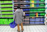 A consumer chooses soft drinks at a supermarket.