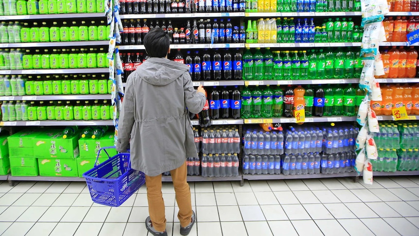 A consumer chooses soft drinks at a supermarket.