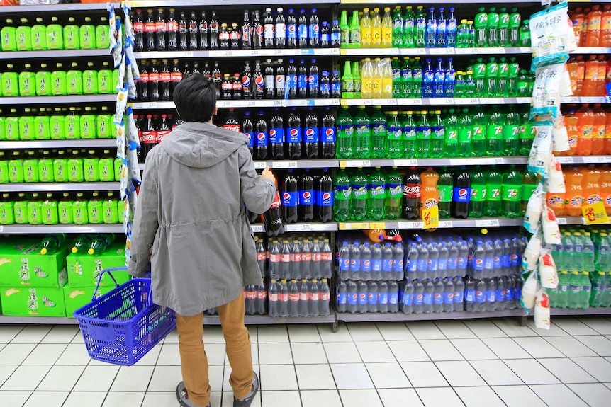 A consumer chooses soft drinks at a supermarket.