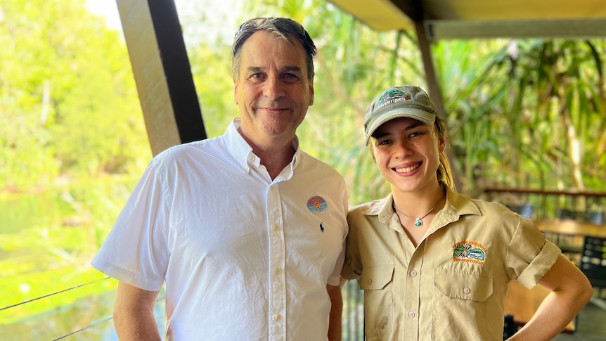 A man wearing a short-sleeved white shirt pictured with a woman wearing khaki in a tropical setting.