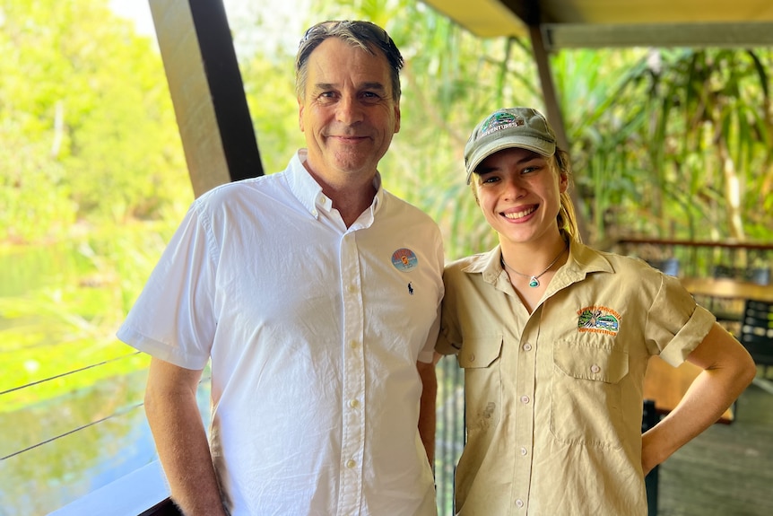 A man wearing a short-sleeved white shirt pictured with a woman wearing khaki in a tropical setting.