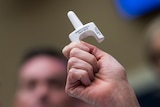 Caucasian hand holding nasal a white nasal spray that contains Naloxone which can reverse the effects of an opioid overdose