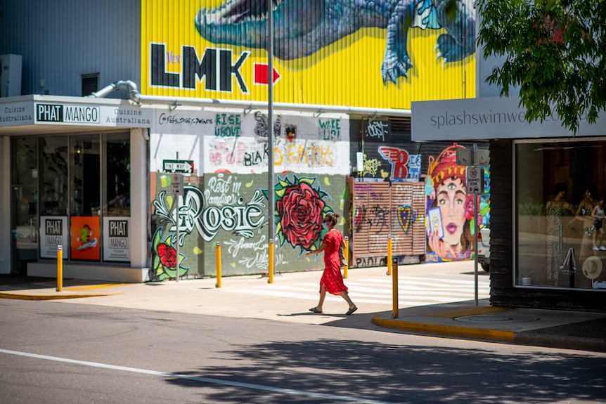 A woman wearing a mask walks along an empty street.