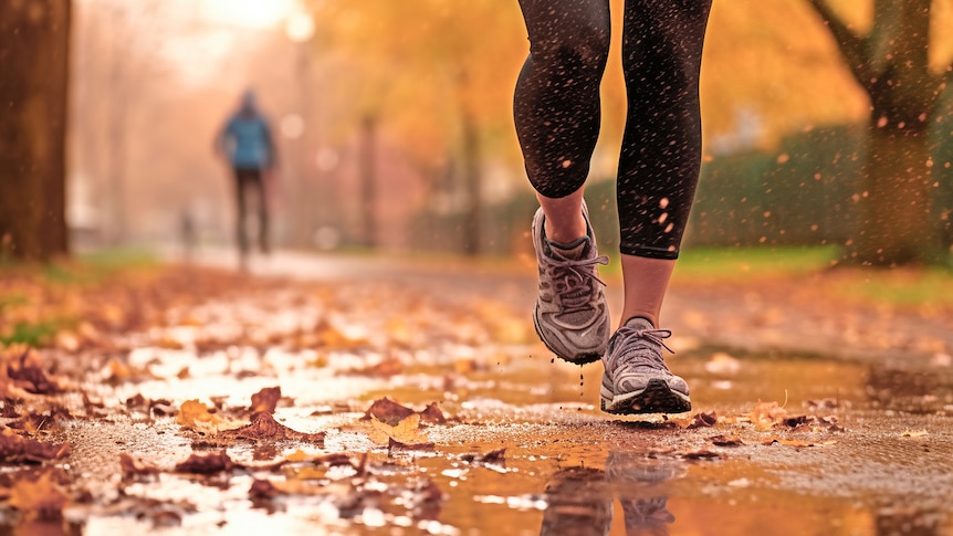 Legs of a female runner jogging in a park on an wet autumn afternoon, the path muddy and wet.