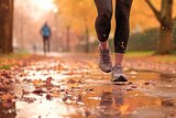 Legs of a female runner jogging in a park on an wet autumn afternoon, the path muddy and wet.