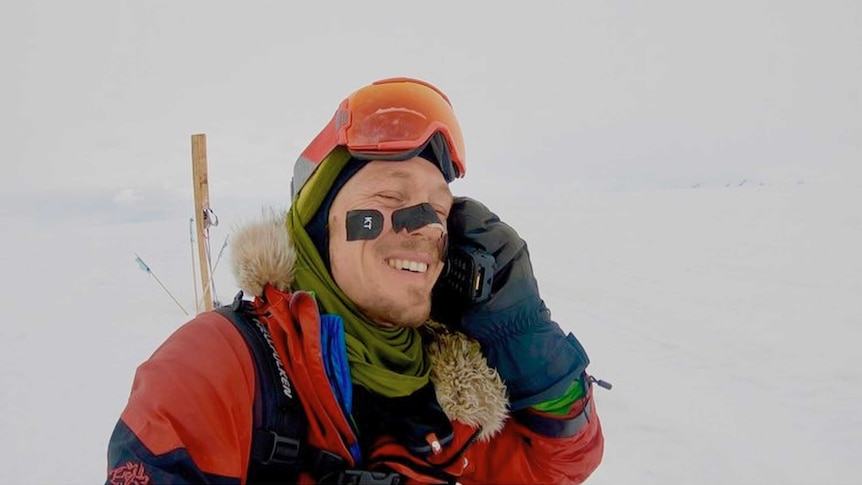 Colin O'Brady smiles as he speaks on the phone in Antarctica.