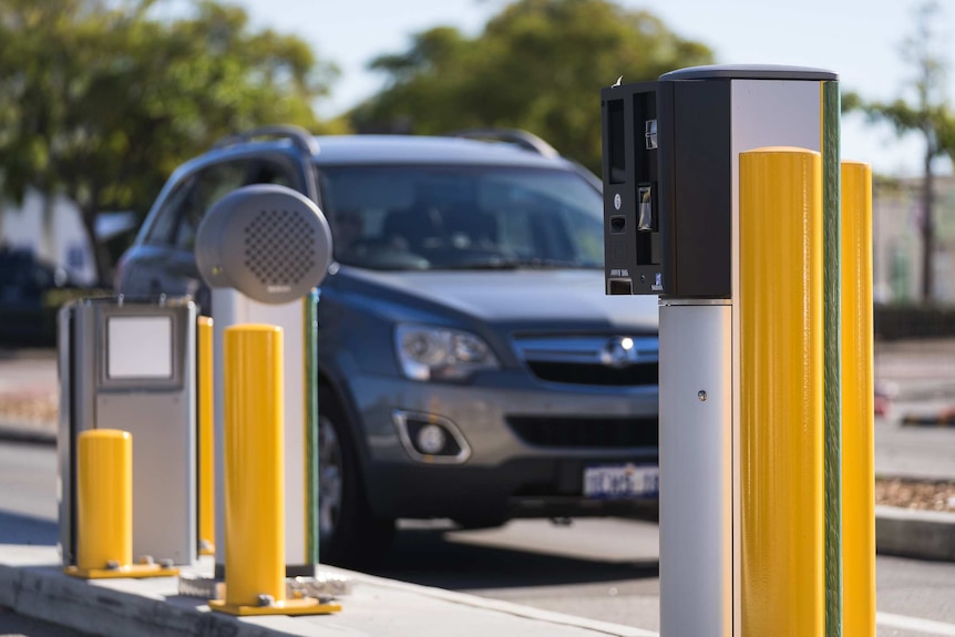 A car pulls up to a shopping centre car park boom gate.