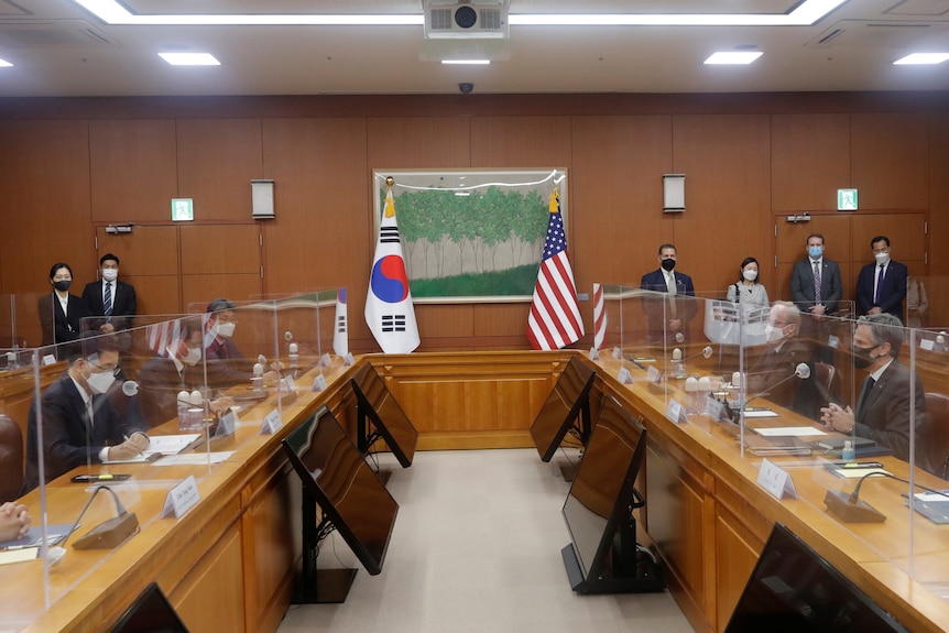 Representatives of the US and South Korean governments sit across from each other in a room.
