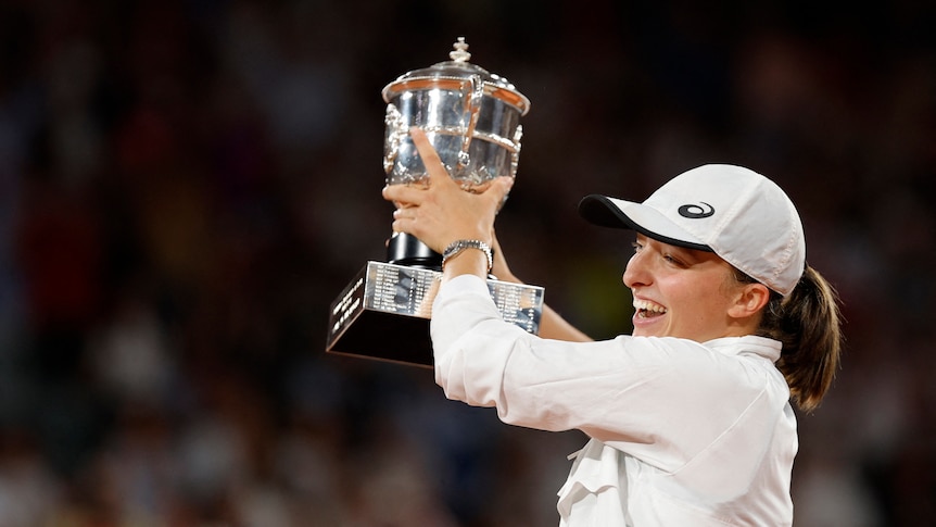Iga Swiatek wears white and holds trophy after winning 2022 French Open
