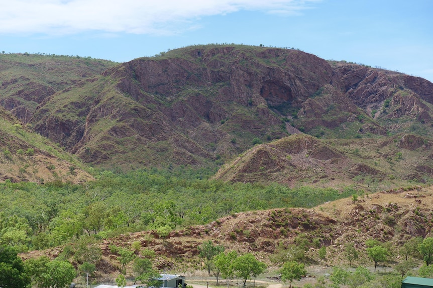 a green valley surrounded by orange hills on the fringe of an indigenous community