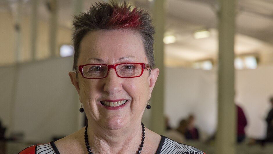 Close up of a woman with a bit of red hair and red glasses