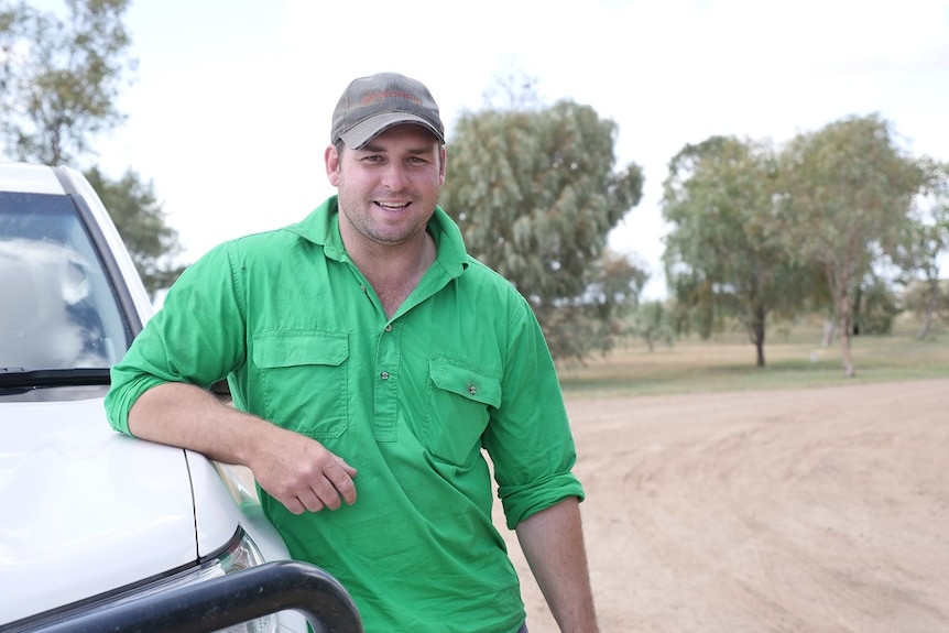 Alexander Corlis leans against a white car, wearing a cap and green shirt.