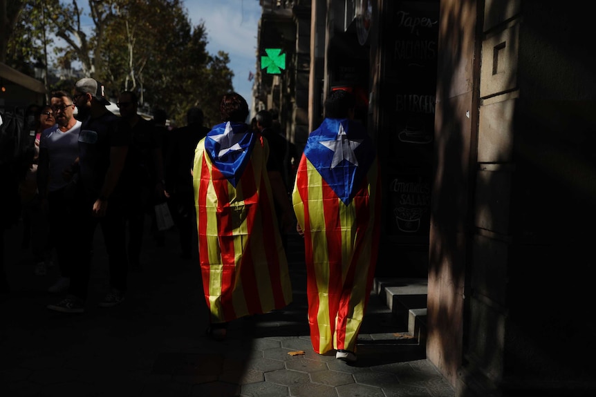 Two people draped in ''estelada'' or Catalonia independence flags.
