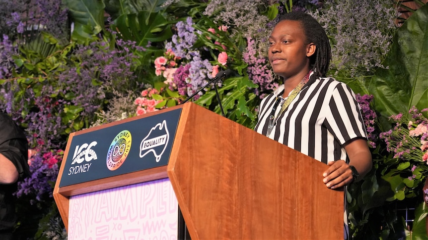 Former Ugandan middle-distance runner Annet Negesa is standing behind a podium, speaking. 