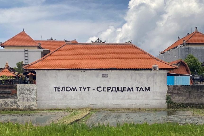 A message written in Russian is painted on the side of a concrete building
