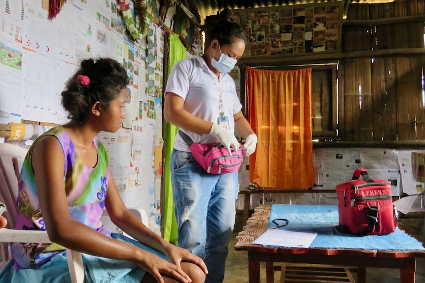 A patient sits inside while a nurse prepares a penicillin injection.