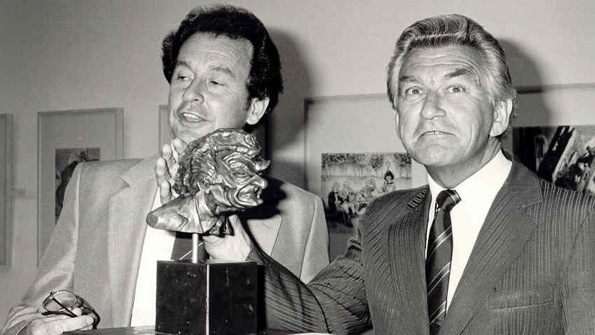 A black and white photo of Bob Hawke examining a bronze sculpture of himself in 1987.