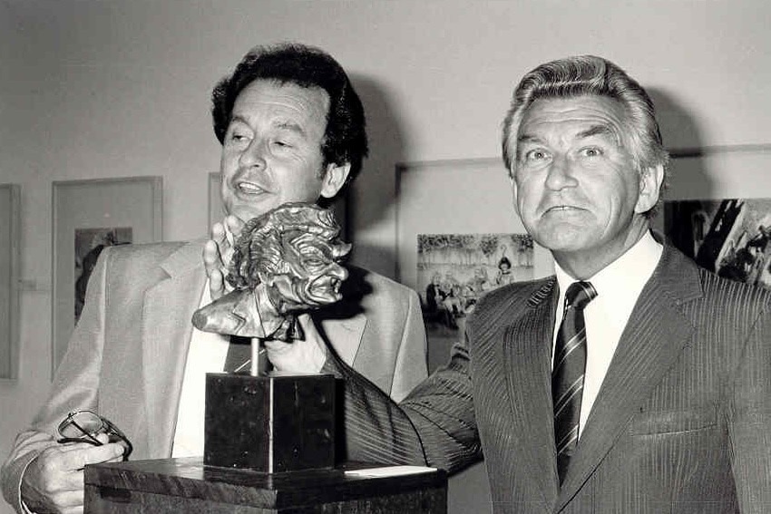 A black and white photo of Bob Hawke examining a bronze sculpture of himself in 1987.
