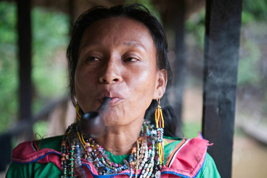 A woman's face close up with a pipe in mouth