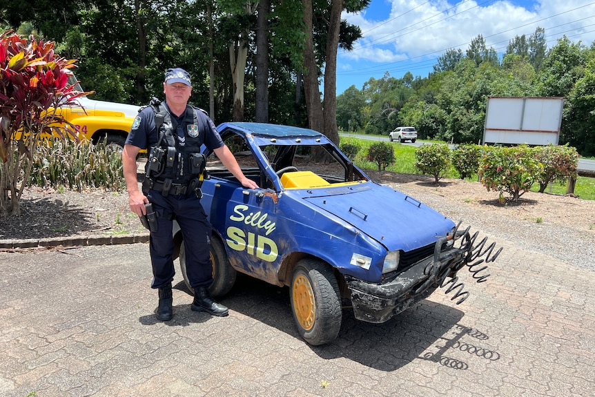 A police officer stands next to a heavily modified vehicle.