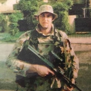 Damien Jordan in his Army fatigues, carrying a rifle